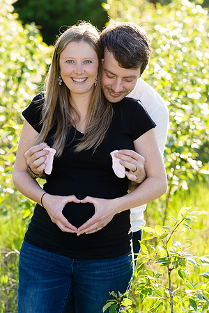 Pregnancy photo of couple making a heart with their hands