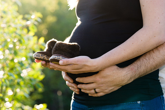 Maternity, expecting couple holding pair of newborn shoes