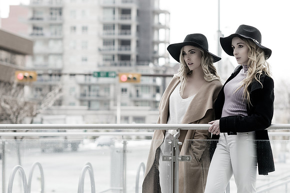 2 blonde fashionable women model in the city with black hats