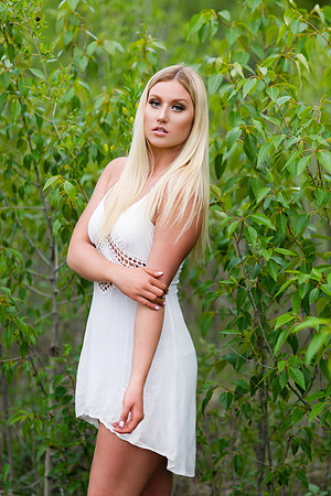 blonde woman in a white summer dress in green fields
