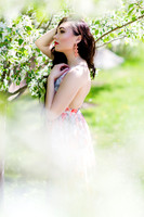 Beautiful brunette model in a beautiful light flower dress surrounded by white blossoms in the spring