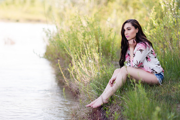 Denim shorts and a pink top with roses, brunette fashion model on the side of the river deep in thought