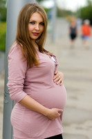 Beautiful pregnant young brunette woman wearing a pink long sleeved shirt in Calgary