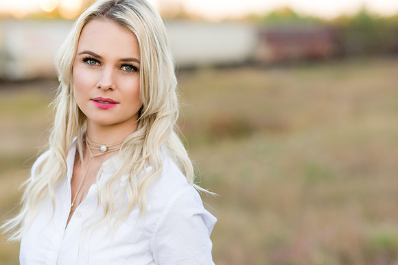 Blonde model in a white blouse in the fall with train in the background