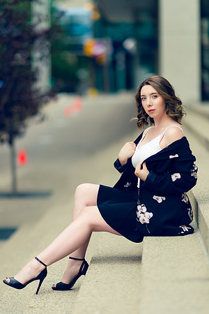Woman brunette model in work outfit and heels downtown sitting on steps