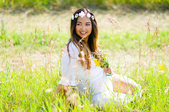 pregnant woman wearing flower crown and a white maternity dress for her maternity shoot